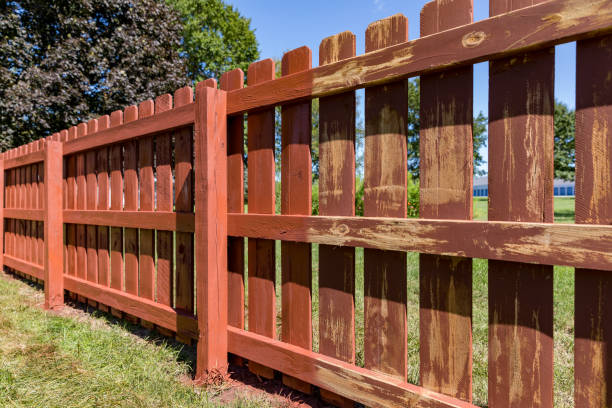 Red-stained picket fence in sunlight